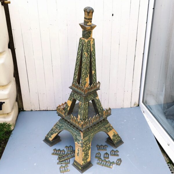 Rare jouet Tour eiffel en bois à construire en trois D composée de 36 pièces, datant de début XXème. Jeux en bois avec papier collé pour les motifs de la Tour, de la célèbre maison HV & W ( Henri Villard et Jules Weill) à Strasbourg , transférée à Luneville après guerre et devenu Majolu. Spécialistes de la fabrication de jouets en bois , solides et durables. Des manque de papiers sur des endroits, des petites casses de bois. Bel état compte tenu de son age mais reste dans jus. Hauteur : 127 cm Largeurs Pieds : 58 cm