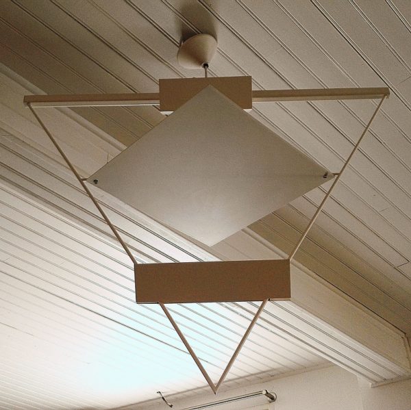 Rare lustre, suspension datant des années 80, dessiné par Mario Botta en métal laqué blanc. Reflecteur inclinable de façon à modifier la luminosité. Un petit manque de peinture sur une pointe du triangle. Excellent état. Hauteur hors fil : 68 cm Largeur : 80 x 50 cm