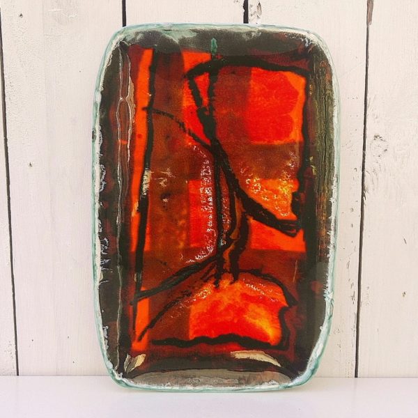 Plat en céramique datant des années 50, à décor abstrait dans les tons chauds de rouge,orange et ocre. Signé sur le dessous. Signature à identifier. Excellent état. Dimensions : 28,5 x 19 cm
