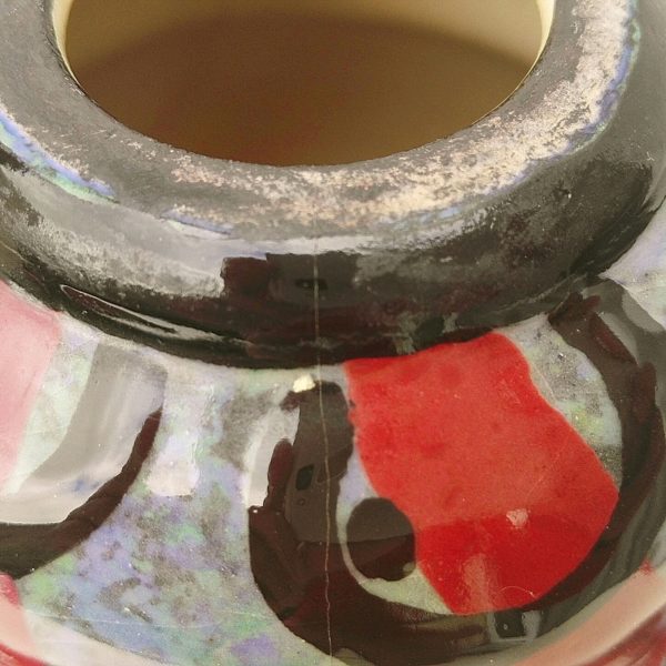 Vase annelé art déco, en céramique émaillée, créé par Louis Dage, à décor de lignes rouge traversant des anneaux noirs, belle épaisseur d'émail. Deux féles au col, signature sur le bas du vase Hauteur : 24,5 cm