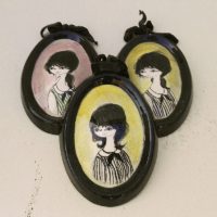 Lot de cinq médaillons en céramique datant des années 50-60, représentant des demoiselles au style et coiffures de cette époque. Chaque médaillons possèdent un noeud en velours noir et une accroche sur l'arrière pour les suspendre au mur. Elégants et romantiques. Signature sur l'arrière. Une micro égrenure sur deux médaillons. Très bon état. Dimensions : 12 x 8,5 cm