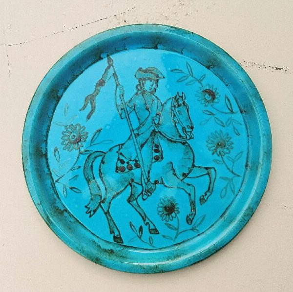 Assiette décorative en céramique, créée par Danuta le Henaff. Décor de cavalier (possiblement Lafayette) en son milieu orné de fleurs. Signée sur le dessous. Excellent état. Diamètre : 24 cm
