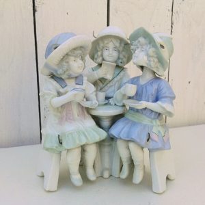 Statuette animée en porcelaine de Saxe, représentant un groupe de trois fillettes prenant le thé. Les têtes dodelinent et jambes se balancent. Un bras a été cassé et recollé. Bon état général. Dimensions : 14 x 10 cm Hauteur : 16 cm