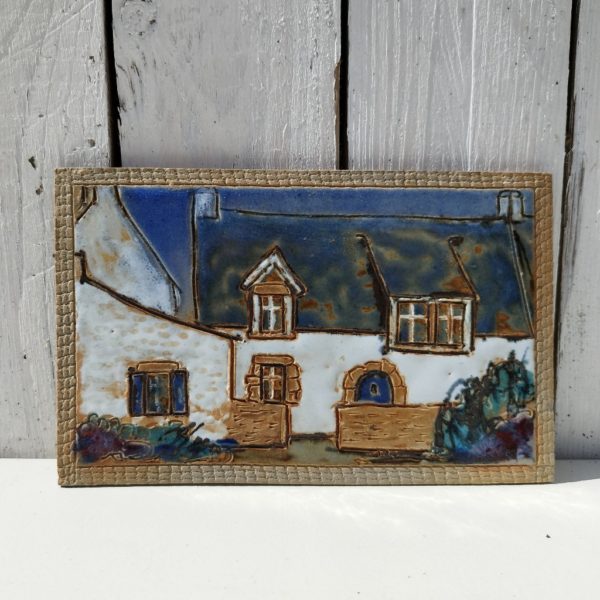 Carreau de céramique représentant une maison typiquement bretonne. Une signature en creux à l'arrière. excellent état. dimensions : 20,5 x 13 cm
