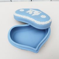 Boite en forme de coeur en biscuit bleu et blanc signé Wedgwood, manufacture anglaise. Avec un décor de personnages à l'antique donnant l'impression d'un camée. Excellent état. Hauteur fermée : 4,5 cm Dimensions boite : 14 x 9 cm