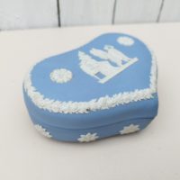 Boite en forme de coeur en biscuit bleu et blanc signé Wedgwood, manufacture anglaise. Avec un décor de personnages à l'antique donnant l'impression d'un camée. Excellent état. Hauteur fermée : 4,5 cm Dimensions boite : 14 x 9 cm