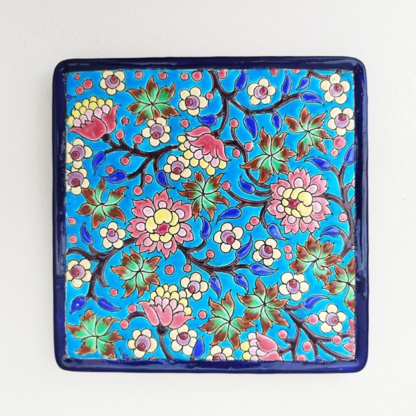Dessous plat en céramique de Longwy, à décor floral émaillé fait à la main. Cachet de la manufacture sur le dessous. Bon état général. Dimensions : 20,5  x 20,5 cm