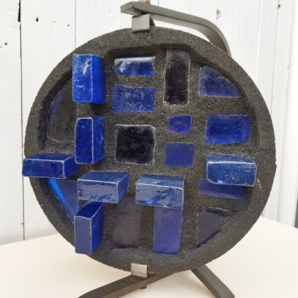 Lampe d'ambiance par Jacques Avoinet, pivotante. Composée d'une structure en fer forgé noir, le diffuseur de lumière est en béton serti de morceaux de verre de couleur bleu. Très bon état. Très lourde.