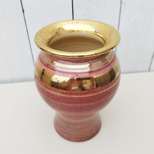 Vase en céramique crée par Georges Pelletier. Dans les tons rose, lie de vin, et dorure craquelée.. Micros égrenures sur le contour du col. Signé sur le pied du vase. Très bon état. Hauteur : 17,5 cm Diamètre : 11 cm