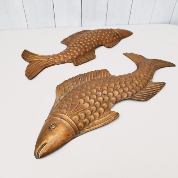 Deux poissons vénitiens en cuivre représentant une carpe, décoration murale vintage. Un trou sur le haut pour les accrocher au mur. Petites rayures et traces d'usage. Dimensions : 42,5 x 16 cm