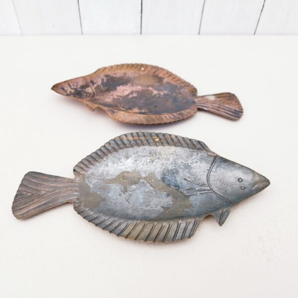Deux poissons vénitiens en cuivre représentant une sole, décoration murale vintage. Un trou sur le haut pour les accrocher au mur. Petites rayures et traces d'usage. Dimensions : 22,5 x 13 cm