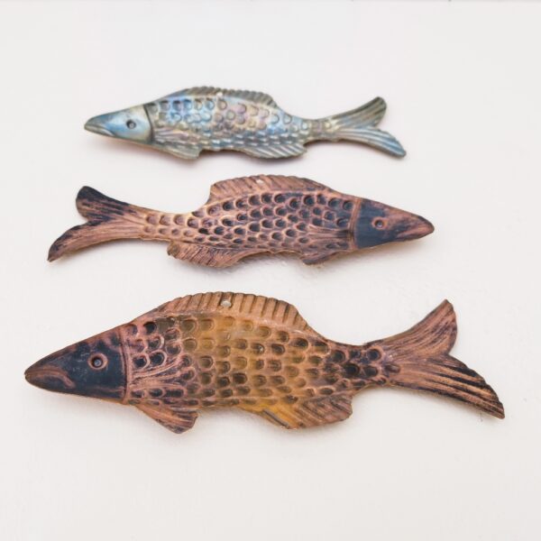 Trois poissons vénitiens en cuivre représentant une truite, décoration murale vintage. Un trou sur le haut pour les accrocher au mur. Petites rayures et traces d'usage. Dimensions : 22 x 8 cm