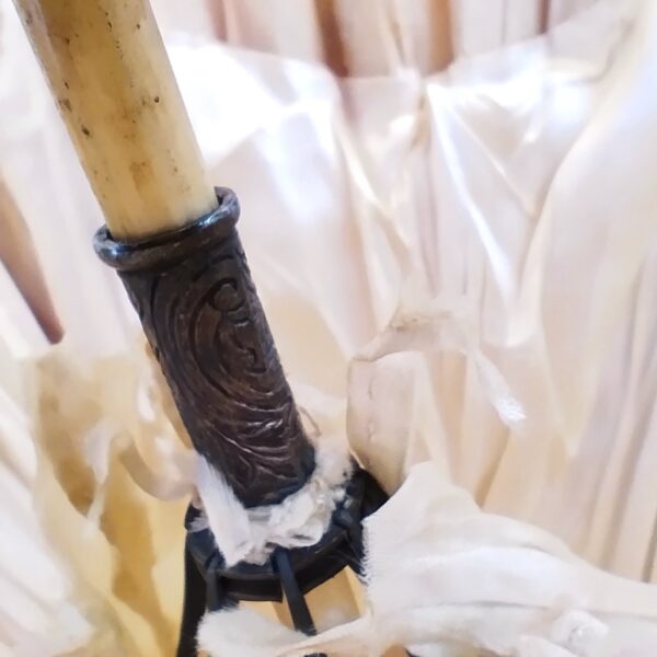 Ancienne ombrelle datant des années 1900-1920, manche en ivoire sculpté à décor de rose, orné d'une bague en argent ou métal argenté à décor floral, se terminant par une boule en ivoire sculpté représentant une rose. Pointe et bouts des baleines de l'ombrelle en ivoire. Un pompon rattaché à la pointe de l'ombrelle. Toile de l'ombrelle en soie. Déchirures de la soie sur l'intérieur et l'extérieur, manque une pointe de baleine, ivoire patiné à nettoyer.Coulant fonctionne bien. Dans son jus Longueur : 62,5 cm