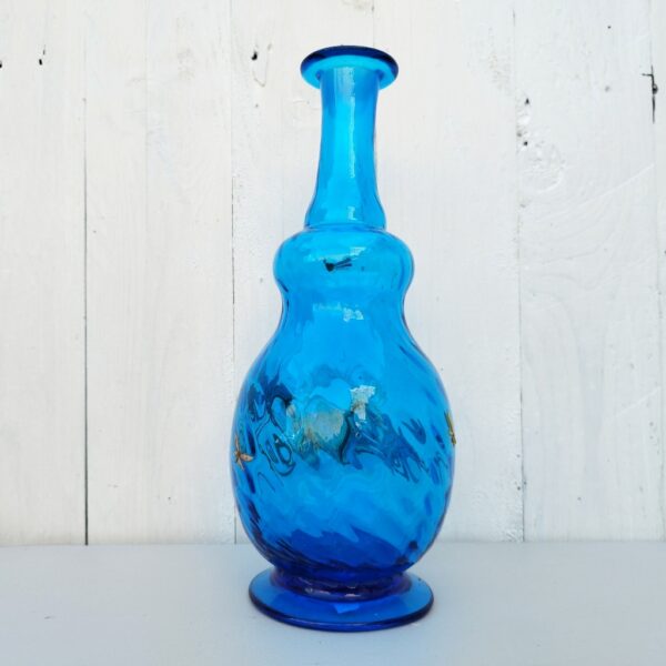 Bouteille ou vase soliflore de couleur bleue à décor émaillé d’angelots tirant sur un bandonéon devant le soleli, rehaussé d’une abeille sur le goulot. Trace de calcaire. Très bon état. Hauteur: 27, 5 cm.