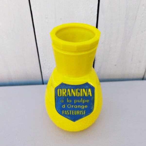 Ancien porte pailles en opaline jaune, publicitaire pour la marque de soda Orangina. A la forme de la célèbre bouteille. Ecusson bleu sur le devant avec l'inscription " Orangina à la pulpe d'orange pasteurisée" Ecusson terni sur les cotés. Bon état général Hauteur : 13,5 cm