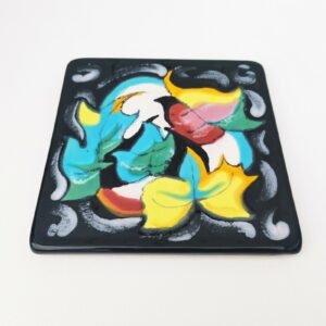 Dessous plat en céramique de Longwy, à décor floral émaillé fait à la main. Intitulé Magie. Cachet de la manufacture sur le dessous. Bon état général. Dimensions : 20,5  x 20,5 cm