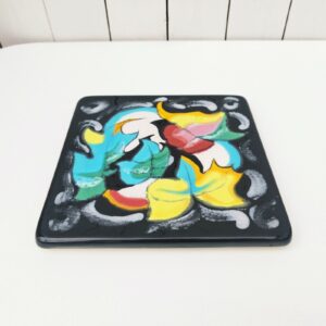 Dessous plat en céramique de Longwy, à décor floral émaillé fait à la main. Intitulé Magie. Cachet de la manufacture sur le dessous. Bon état général. Dimensions : 20,5  x 20,5 cm