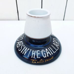 Pyrogène publicitaire pour l'absinthe Gaillard des années 40-50. Ecriture émaillée en relief. Un tache à l'intérieur du réceptacle à allumettes. Très bon état. Hauteur : 9 cm Diamètre base : 11,5 cm