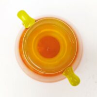 Vase à anse en verre soufflé, dans des tons très acidulés orange et jaune. Décor marmoréen. Signé à la pointe sur le bas, datant des années 20. Excellent état. Hauteur : 14 cm Diamètre  : 12,8 cm