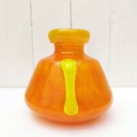 Vase à anse en verre soufflé, dans des tons très acidulés orange et jaune. Décor marmoréen. Signé à la pointe sur le bas, datant des années 20. Excellent état. Hauteur : 14 cm Diamètre  : 12,8 cm