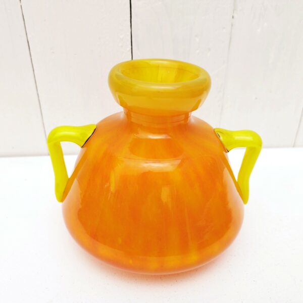 Vase à anse en verre soufflé, dans des tons très acidulés orange et jaune. Décor marmoréen. Signé à la pointe sur le bas, datant des années 20. Excellent état. Hauteur : 14 cm Diamètre  : 12,8 cm