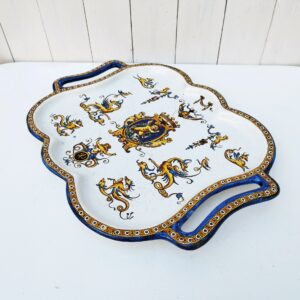Ancien plat de service en faïence de Gien, décor de chimères et d'angelots. Richement orné. Tampon sur le dessous. Rayures d'usage, un fêle sur le haut sans gravité. Bon état général Dimensions avec poignées : 42 x 32,5 cm