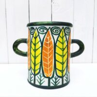 Vase ou pot à anse en céramique, à décor de feuilles colorées jaunes et orange. Un micro éclat sur le dessous, non visible une fois posé.  Très bon état.  Hauteur : 16 cm Diamètre : 12, 5 cm