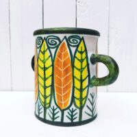 Vase ou pot à anse en céramique, à décor de feuilles colorées jaunes et orange. Un micro éclat sur le dessous, non visible une fois posé.  Très bon état.  Hauteur : 16 cm Diamètre : 12, 5 cm