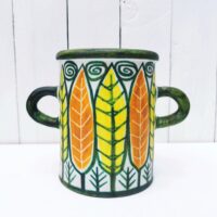 Vase ou pot à anse en céramique, à décor de feuilles colorées jaunes et orange. Un micro éclat sur le dessous, non visible une fois posé.  Très bon état.  Hauteur : 16 cm Diamètre : 12, 5 cm
