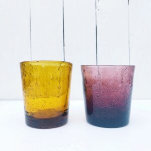 Deux verres à whisky en verre soufflé de la verrerie de Biot. Les bulles dans le verre sont typiques de cette manufacture. L'un ambré et l'autre dans les tons prunes De très belle facture, ils sont assez lourd Très bon état. Hauteur : 10 cm Diamètre 8,5 cm