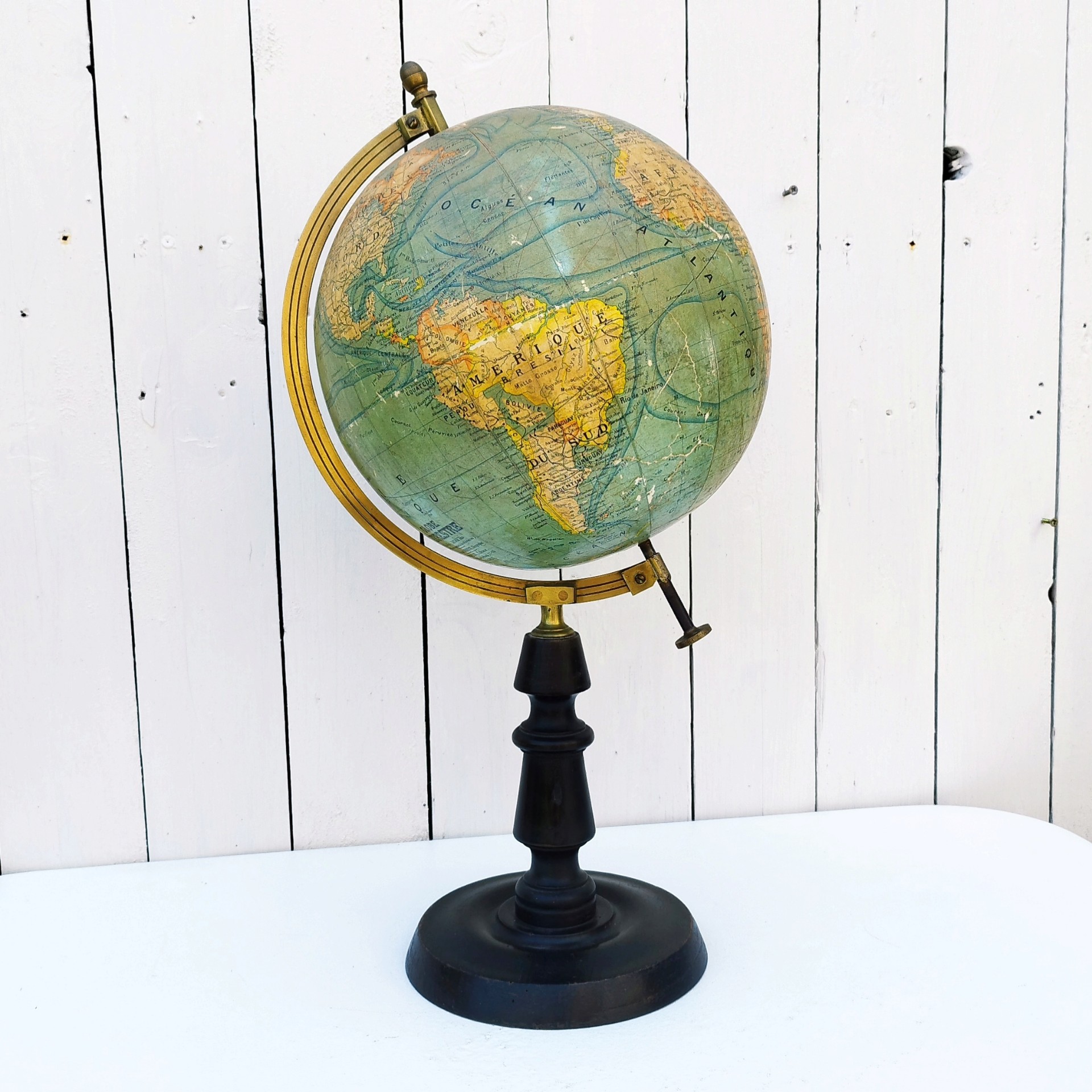 Grand globe Napoléon III en carton recouvert de la carte du monde en papier, pivotant sur un pied en bois noirci , entouré d'une réglette en laiton crée par J.Forest et édité par lui même. Usure du papier sur le dessus du globe, quelques petits manques de papier. Bon état général. Hauteur : 50 cm Diamètre : ~23 cm