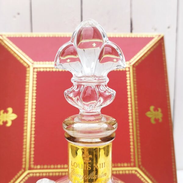 Belle bouteille de cognac en cristal de Baccarat créée par Remy Martin modèle Louis XIII , rehaussé de cabochons fleurs de lys, Bouchon fleur de lys, signé et numéroté. Coffret d'origine. Bouteille signée et numérotés. Très beau cadeau pour un amateur de cognac. Très bon état. Hauteur bouteille sans bouchon : 19 cm Dimensions coffret : 27 x 27 x  9,5 cm