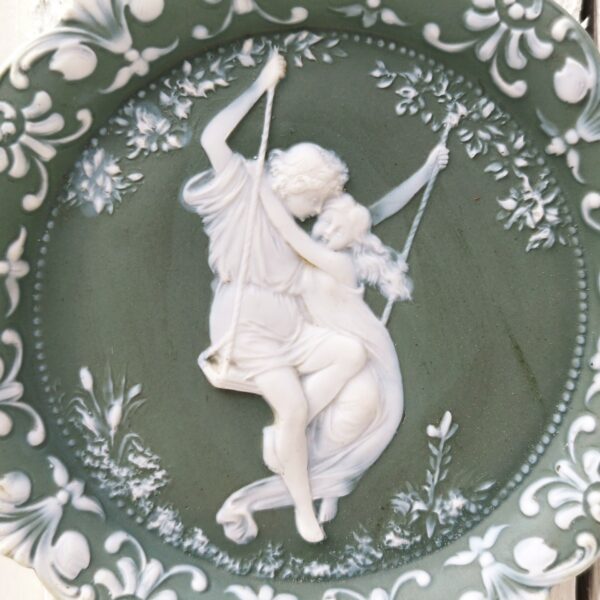 Médaillon rond à suspendre en biscuit de la manufacture anglaise Wedgwood, représentant une scène romantique. Petits défauts de cuisson Très bon on état général Diamètre : 12 cm