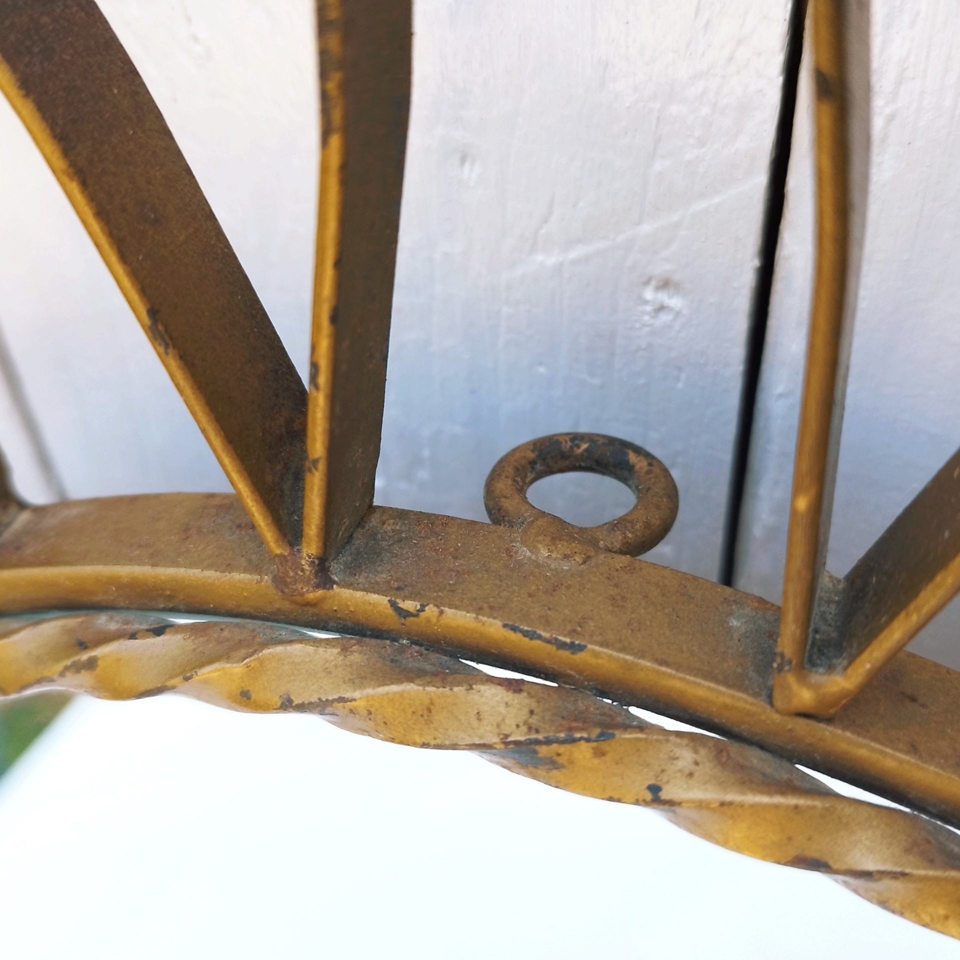 Grand miroir soleil, oeil de sorcière, en métal doré datant des années 50.  Traces de corrosion et manques de dorures. une rayure sur le miroir. Un point d'accroche sur l'arrière. Une soudure a sauté Dans son jus Diamètre total : 74 cm Diamètre miroir : 26 cm