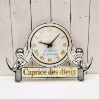 Rare pendule publicitaire pour la marque de fromages Caprice des dieux.  Pendule entourée de deux anges marqué Caprice de Dieux en lettres dorées. Des manques de peintures, des rayures et chocs d'usage. Le mécanisme de la pile est à changer car ne fonctionne pas (facilement trouvable sur internet ou magasin de bricolage) Etat d'usage. Dimensions : 41,5  x 27 cm