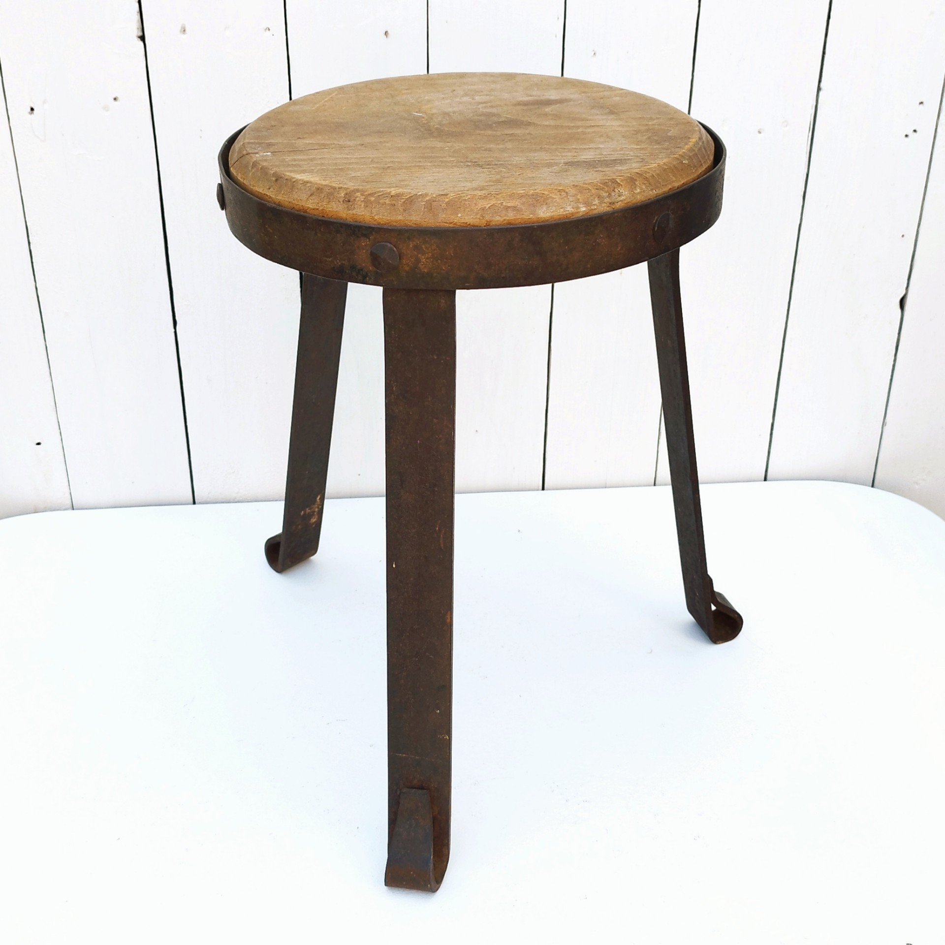 Petit tabouret brutaliste avec assise en bois patiné, cerclage  et pieds en fer forgé. Décoration très campagne ou très Loft. Patine d'origine. Un boulon a été changé. Bon état général. Hauteur : 38 cm Diamètre : 27 cm