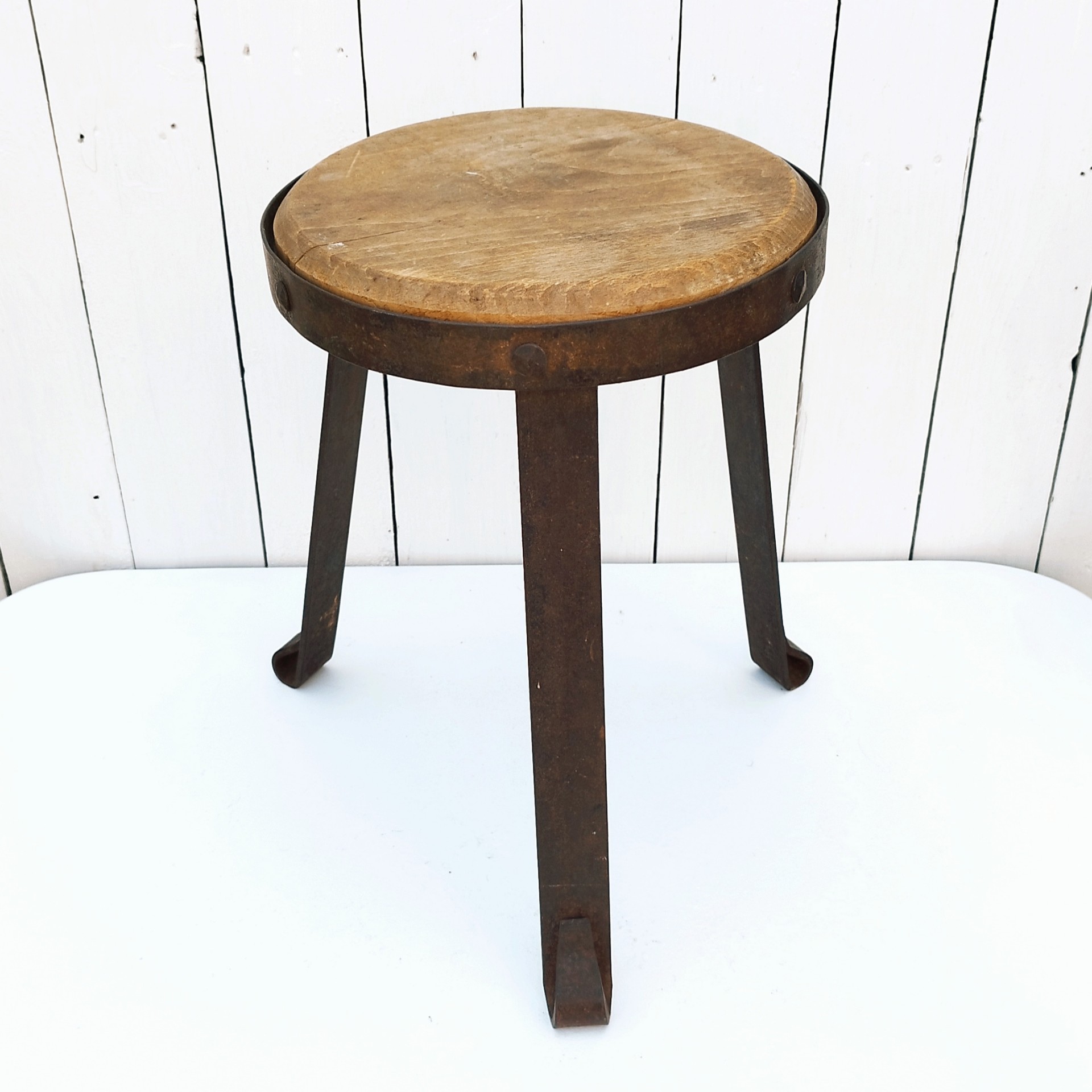 Petit tabouret brutaliste avec assise en bois patiné, cerclage  et pieds en fer forgé. Décoration très campagne ou très Loft. Patine d'origine. Un boulon a été changé. Bon état général. Hauteur : 38 cm Diamètre : 27 cm