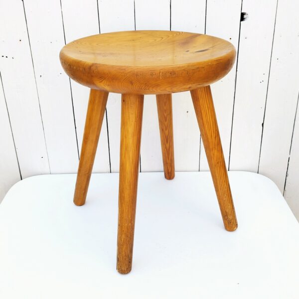 Tabouret vintage quadripode en pin. Assise creusée lui conférant un bon confort. Très belle patine du bois. Tabouret faisant penser au travail de Charlotte Perriand Traces et rayures d'usage. Bon état général. Hauteur : 46,5 cm Diamètre : 36,5 cm