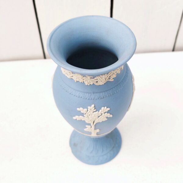 Vase en biscuit bleu et blanc signé Wedgwood, manufacture anglaise. Avec un décor de personnages à l'antique donnant l'impression d'un camée. Un petit éclat au pied. Hauteur : 14,5 cm