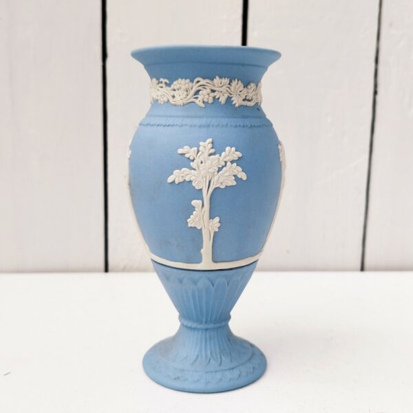 Vase en biscuit bleu et blanc signé Wedgwood, manufacture anglaise. Avec un décor de personnages à l'antique donnant l'impression d'un camée. Un petit éclat au pied. Hauteur : 14,5 cm