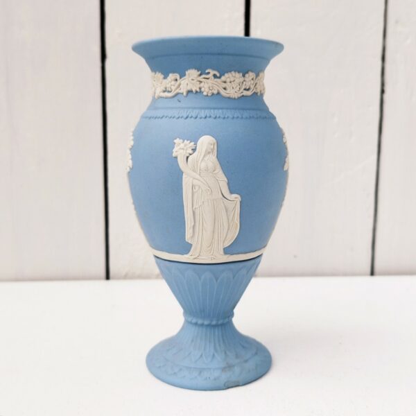 Vase en biscuit bleu et blanc signé Wedgwood, manufacture anglaise. Avec un décor de personnages à l'antique donnant l'impression d'un camée. Un petit éclat au pied. Hauteur : 14,5 cm