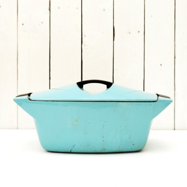 Cocotte en fonte émaillée de couleur turquoise datant des années 50, dessinée par Raymond Loewy pour Le Creuset. Contenance de 3,5 litres. Poignée du couvercle en bakélite. Des petits éclats sur le contour du couvercle. Une petite fêlure sur une poignée sans gravité. Bon état général. Longueur avec poignées : 32,5 cm Longueur sans poignées : 26 cm Largeur : 20,5 cm Hauteur : 10 cm