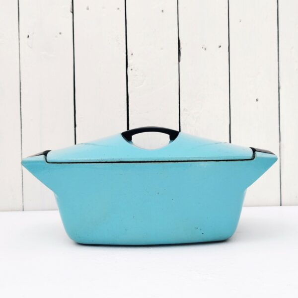 Cocotte en fonte émaillée de couleur turquoise datant des années 50, dessinée par Raymond Loewy pour Le Creuset. Contenance de 3,5 litres. Poignée du couvercle en bakélite. Des petits éclats sur le contour du couvercle. Une petite fêlure sur une poignée sans gravité. Bon état général. Longueur avec poignées : 32,5 cm Longueur sans poignées : 26 cm Largeur : 20,5 cm Hauteur : 10 cm