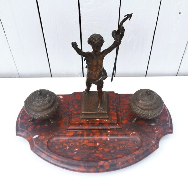 Grand encrier en bronze et socle en marbre représentant Saint Jean Baptiste enfant. Fondeur Susse Frères. La charnière du couvercle de l'encrier doit a du jeux. La croix de Saint Jean Baptiste est pliée et est cassée au niveau de la main. Bon état général. Dimensions : 29 x 38 x 20 cm