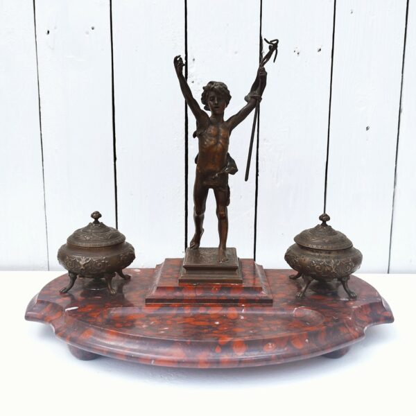 Grand encrier en bronze et socle en marbre représentant Saint Jean Baptiste enfant. Fondeur Susse Frères. La charnière du couvercle de l'encrier doit a du jeux. La croix de Saint Jean Baptiste est pliée et est cassée au niveau de la main. Bon état général. Dimensions : 29 x 38 x 20 cm