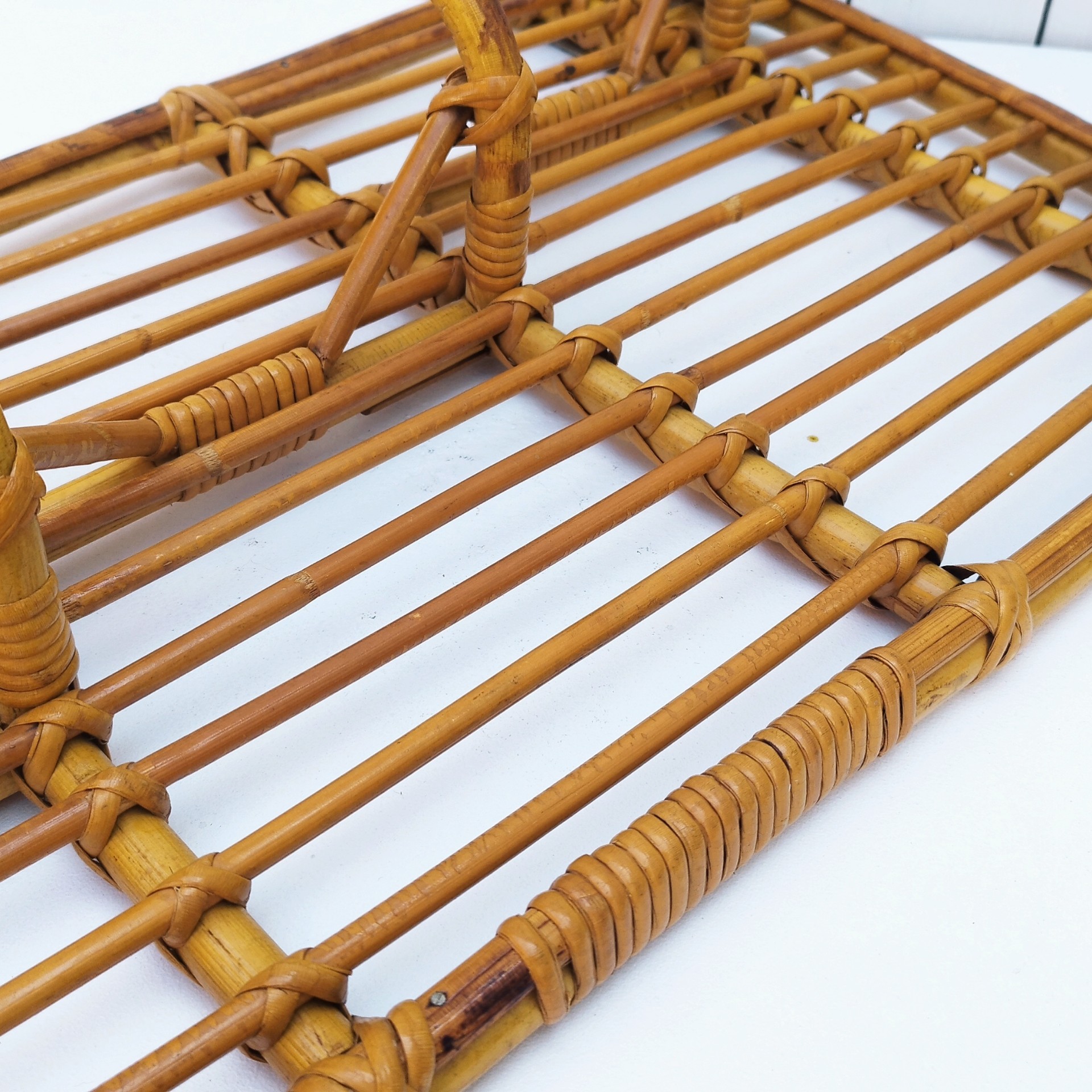 Grand porte-manteaux en rotin, 4 patères. Datant des années 60. Deux accroches murales. Manque un lien sur le coté gauche au niveau de la patère, a été refixé avec une pointe et collé. Bon état général. Longueur : 75 cm hauteur max : 40 cm Hauteur min : 30 cm