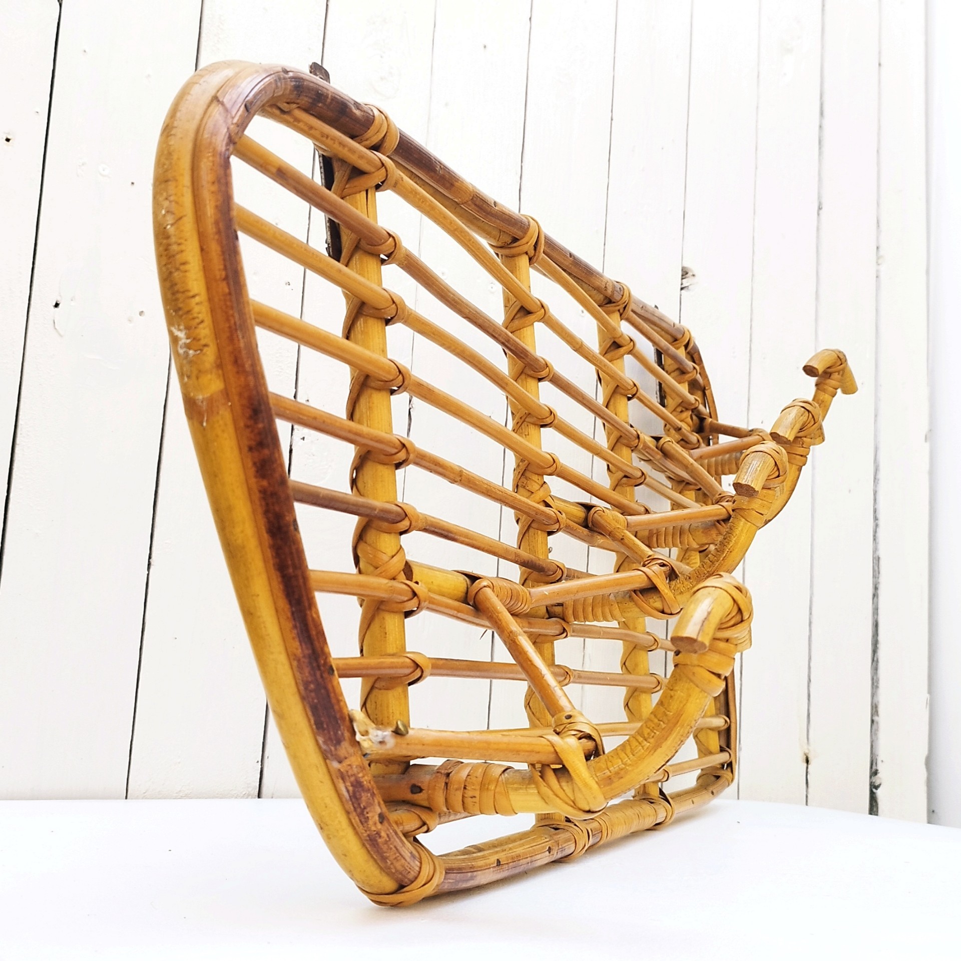 Grand porte-manteaux en rotin, 4 patères. Datant des années 60. Deux accroches murales. Manque un lien sur le coté gauche au niveau de la patère, a été refixé avec une pointe et collé. Bon état général. Longueur : 75 cm hauteur max : 40 cm Hauteur min : 30 cm