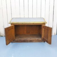 Meuble de cireur de chaussures, avec sur son sommet une plaque de zinc inclinée et rainurée pour cirer et nettoyer ses chaussures avec facilité. Deux porte sur le bas. Meuble entouré de laiton doré. Très belle patine. Petites de corrosion sur le laiton sans gravité. Traces d'usage  bon état. Hauteur : 46 cm Longueur : 70 cm Profondeur : 35 cm