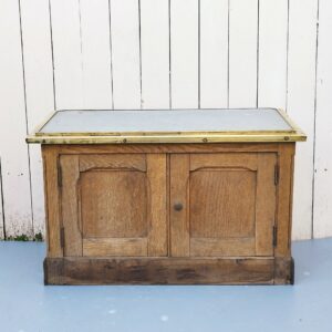 Meuble de cireur de chaussures, avec sur son sommet une plaque de zinc inclinée et rainurée pour cirer et nettoyer ses chaussures avec facilité. Deux porte sur le bas. Meuble entouré de laiton doré. Très belle patine. Petites de corrosion sur le laiton sans gravité. Traces d'usage  bon état. Hauteur : 46 cm Longueur : 70 cm Profondeur : 35 cm