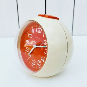 Réveil boule datant des années 70  en plastique blanc/crème et cadran orange Fonctionnne parfaitement, sonnerie pas trop agressive. Aiguilles et numérotations phosphorescentes Quelques rayures d'usage. Excellent état. Hauteur : ~ 13 cm